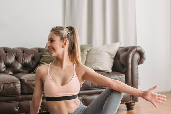 A person in comfortable sportswear stretching on a mat.